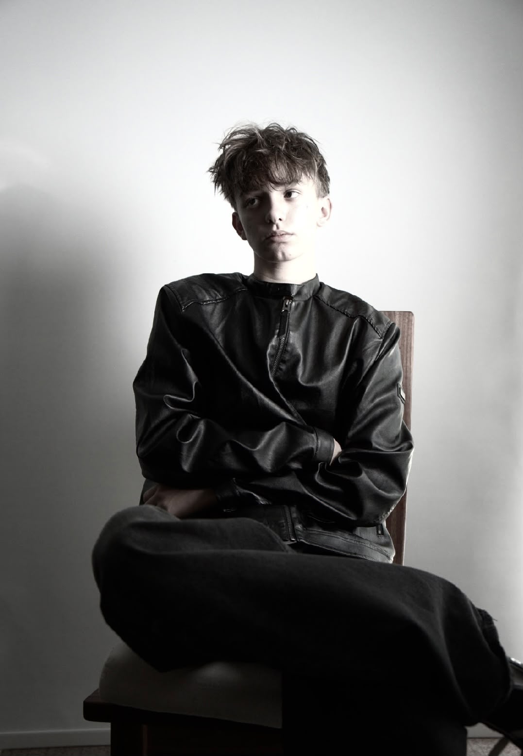 Studio portrait of Teo Ladrière seated, wearing a leather jacket